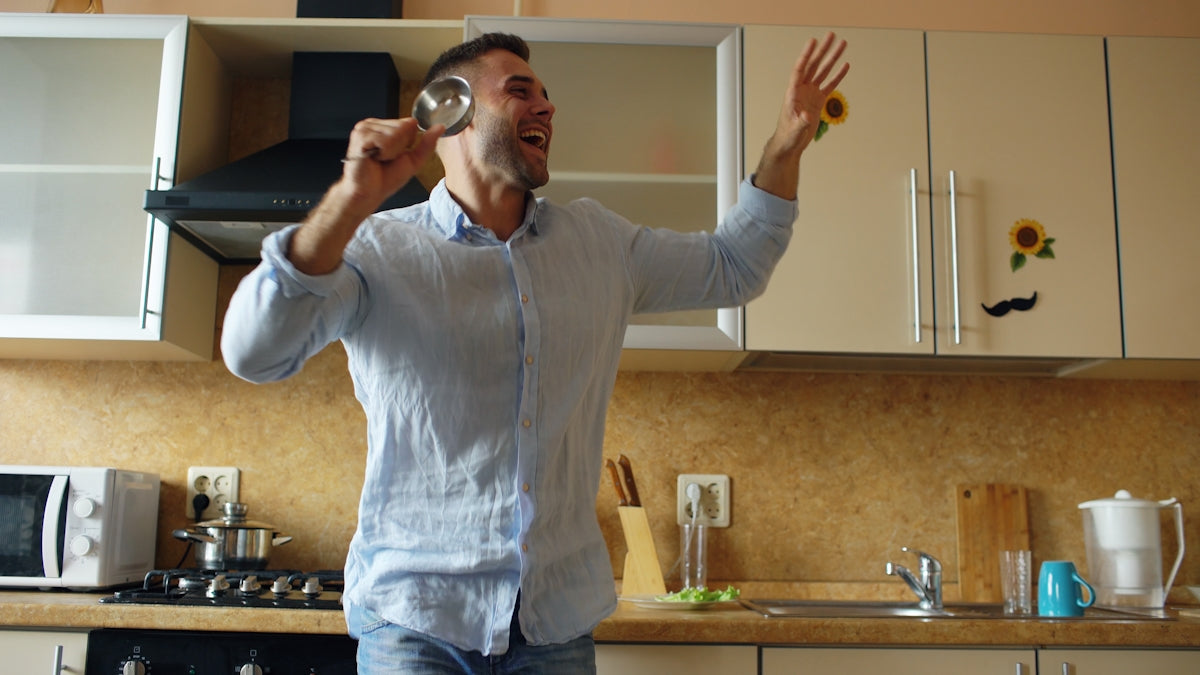 Man singing and dancing in a kitchen.